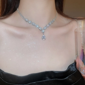Detailed close-up of a silver Y-shaped drop necklace with zircon stones on a black dress