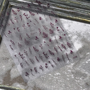 Detailed view of translucent nail art sticker featuring dark red floral and leaf patterns