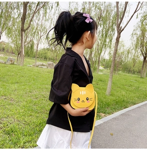 Outdoor model showing a cute yellow cartoon cat crossbody bag for kids in a park