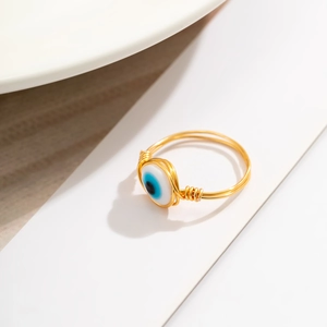 Close-up of handmade gold wire-wrapped ring with a blue evil eye bead detail