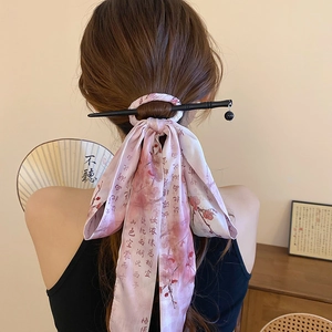 Detail of pink silk ribbon with plum blossoms and black wooden hairpin for hair styling