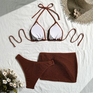 Detailed close-up of brown crinkle fabric three-piece bikini with matching mini skirt