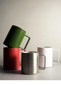 Detail of four colorful insulated mugs with square handles and internal measurement scales