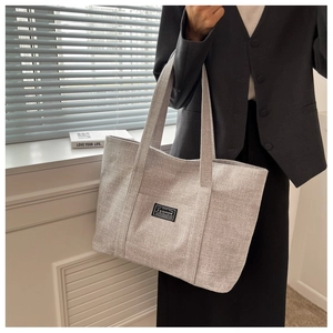 Close-up of a grey canvas tote bag showing textured fabric and fashion label detail