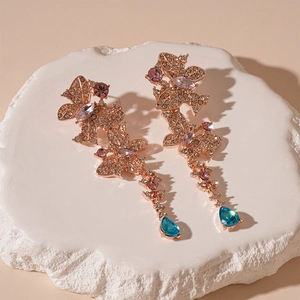 Detail of butterfly drop earrings with multi-color rhinestones on a white rock base