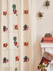 Detail of embroidered Santa Claus patterns and wavy lace edges on semi-sheer Xmas curtains