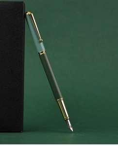 Close-up of a business metal fountain pen in dark green and gold on a premium gift box