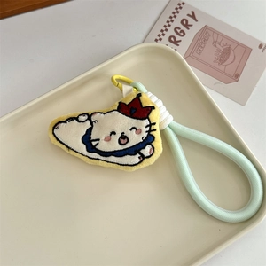 Detail view of a white plush cat keychain with a red crown and green woven strap
