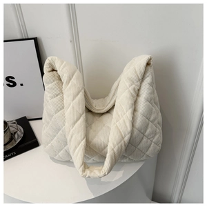 Detail of white quilted corduroy tote bag showing diamond stitch texture on a minimalist table