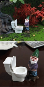 Funny resin gnome sitting on a miniature toilet ornament for garden landscape decor