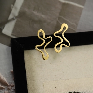 Macro shot of gold irregular wave earrings with a high-gloss metallic finish on display
