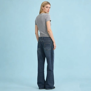 Detail of wide-leg dark blue denim jeans showing back pocket design and baggy fit