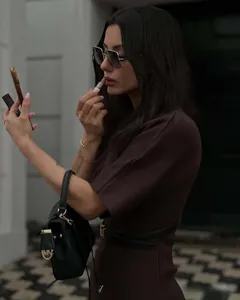 Detail of a brown short-sleeved dress with a black waist belt and a leather handbag