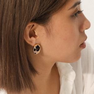 Oval 18K gold-plated leopard print earrings worn by a model in a minimalist style