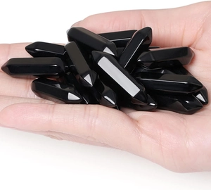 Close-up of polished black obsidian hexagonal double point crystal columns held in hand