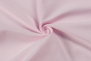 Close-up of soft pink knitted fabric with textured patterns and gentle drape detail