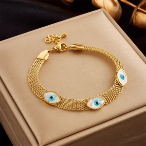 Detailed close-up of a gold link bracelet with evil eye charms on a metallic box