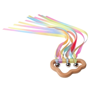 Close-up of wooden cloud handle with rainbow ribbons and silver bells for baby sensory play