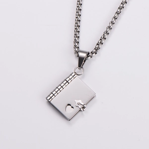 Close-up of a silver book pendant necklace featuring a heart cutout and hinge details