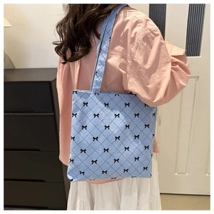 Dettaglio borsa tote in velluto blu con trapuntatura a rombi e piccoli fiocchi neri