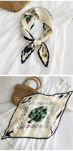 Dettaglio del foulard in seta a pieghe con stampa di foglie verdi e bordo a onde