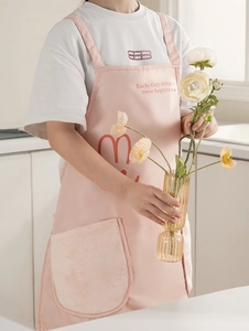 Detail of pink kitchen apron with plush pocket and motivational quote on chest