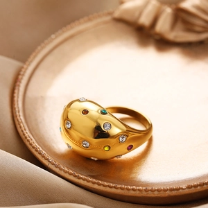 Macro detail of gold-plated teardrop ring with colorful zircons on silk background