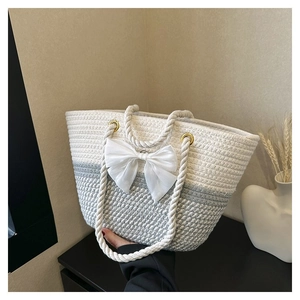 Detail of woven tote bag featuring dual-tone texture and a large white decorative bow