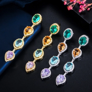 Macro view of long dangling earrings with colorful zircon stones on silk background