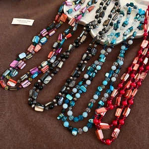 Close-up of bohemian beaded necklaces featuring colorful shell charms and round beads