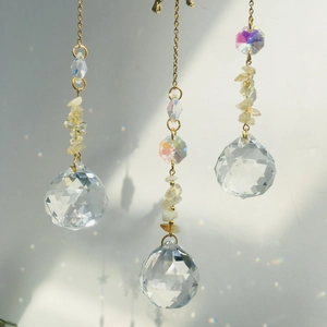 Macro view of crystal suncatchers with metal chains reflecting rainbow light on a wall