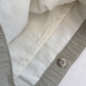 Detail view of large canvas bag featuring grey-green exterior and magnetic metal buckle
