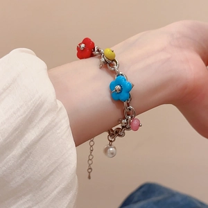 Detail of a floral charm bracelet with colorful beads and a pearl on a model's wrist
