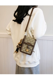 Detail of vintage bear pattern canvas crossbody phone bag with cute charm and gold buckle