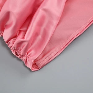Gros plan sur le satin rose montrant la texture soyeuse et les détails de fronces
