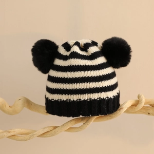 Dettaglio del cappello in maglia per neonati a righe bianche e nere con due pompon
