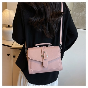 Pink structured square handbag with pebbled texture shown on a model in cozy room setting
