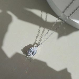 Vue macro d'un pendentif en zircon poire sur chaîne argentée avec reflets arc-en-ciel