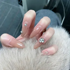 Nude long almond press-on nails with silver floral rhinestones held against plush fur