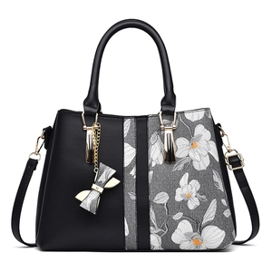 Women's handbag with elegant orchid print, black leather handles and bow charm ornament