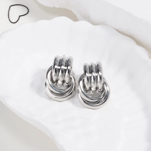 Detailed shot of silver triple-hoop earrings displayed on a white shell-shaped plate