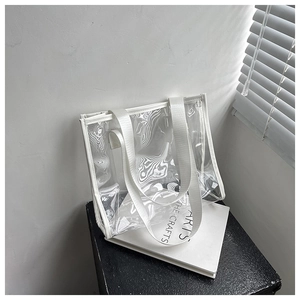 Detail of transparent PVC tote bag with white woven handles in minimalist lighting