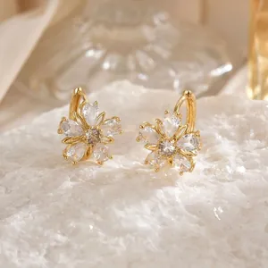Elegant gold flower stud earrings with sparkling zircon petals on white stone base