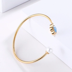 Detail of adjustable gold bangle with blue crystal petals and a white pearl accent