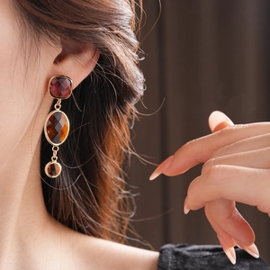 Primo piano di orecchini vintage pendenti in vetro ambrato indossati da una modella