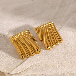 Detail shot of vintage gold-plated scalloped earrings on textured stone surface