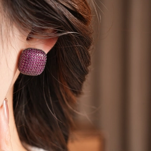 Vue latérale macro de boucles d'oreilles vintage carrées en zircon magenta sur modèle
