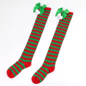 Detail of red and green striped Christmas over-knee socks with bows and white pom-poms
