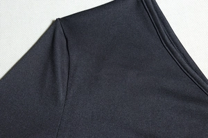 Close-up of fine stitching and black synthetic knit fabric on one-shoulder dress