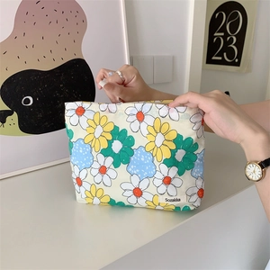 Floral cotton makeup bag with yellow and blue sun flower pattern held in hand